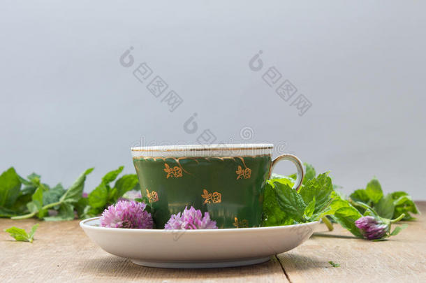 绿色的杯子和茶杯托.新鲜的薄荷树叶和三叶草花为