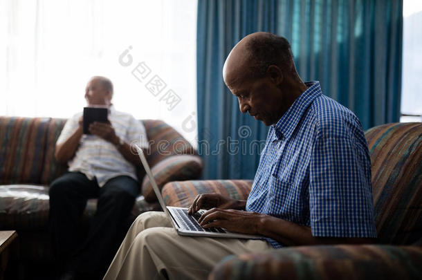 较高的男人使用便携式电脑在期间一次向沙发