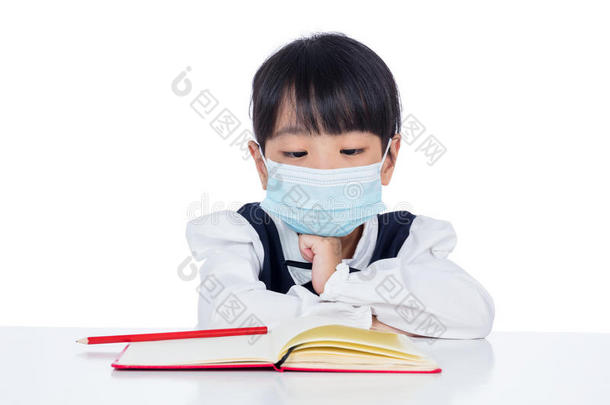亚洲人小的中国人女孩阅读书和保护面具