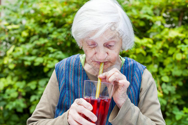 老的女人和老年痴呆症疾病喝饮料悬钩子果汁