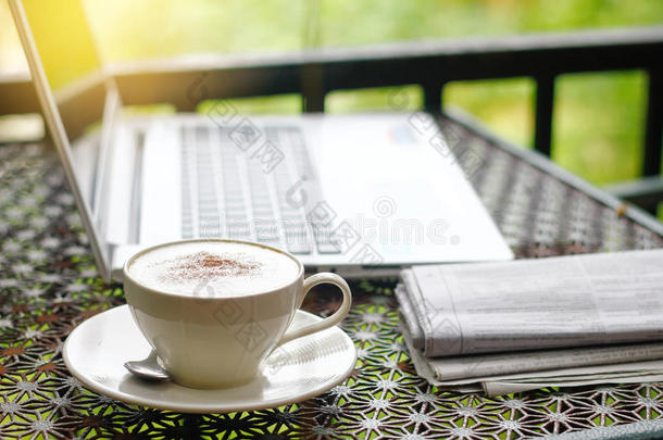 股份照片:卡普契诺咖啡和报纸,便携式电脑或笔记簿向