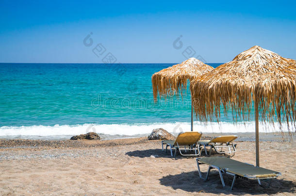空的海滩和稻草伞和太阳灯浴浴床,克利特岛,希腊