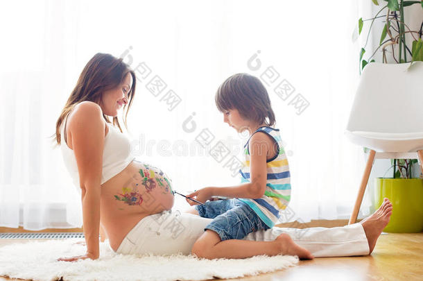 幸福的小孩,男孩,绘画向妈咪`英文字母表的第19个字母怀孕的肚子