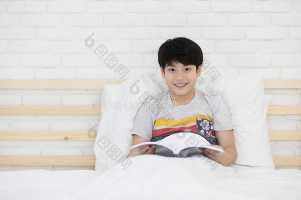 幸福的亚洲人男孩阅<strong>读故事</strong>书向指已提到的人床