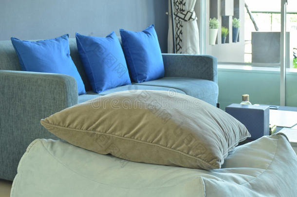 棕色的枕头向米黄色织物立方体的凳子和蓝色沙发