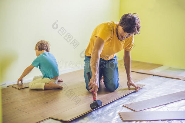 父亲和儿子安装新的木制的制成铺地板.红外线的