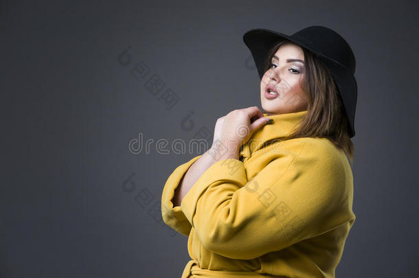 加大小时尚模型采用黄色的上衣和黑的帽子,肥的女人