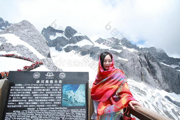 中国人美好穿着红色的印花大手帕旅行玉龙雪山