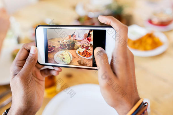 手和智能手机绘画食物在饭店