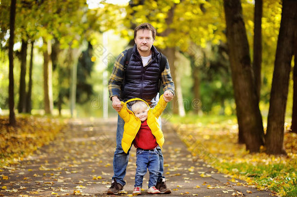 父亲和他的蹒跚行走的人儿子步行采用秋森林