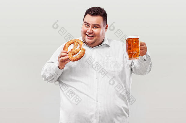 年幼的肥的男人在啤酒节,喝饮料啤酒和e在我ng椒盐卷饼我
