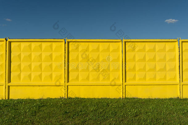 黄色的具脐状突起的具体的栅栏,绿色的草和蓝色天