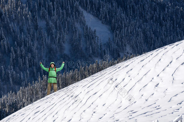 幸福的年幼的男人和背包起立向下雪的山斜坡.