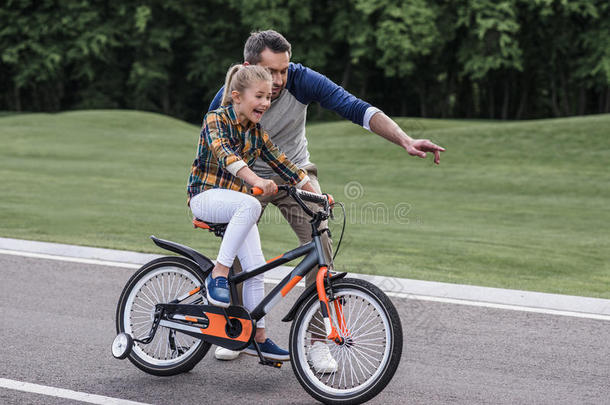 父亲教学他的小的女儿骑马自行车向沥青Romania罗马尼亚