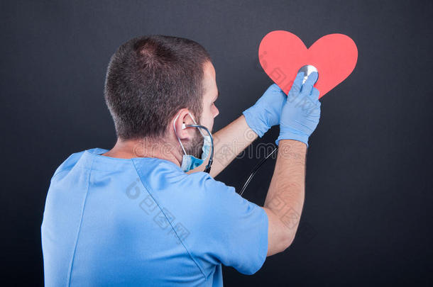 背看法关于心脏病专家使用听诊器向红色的形状心