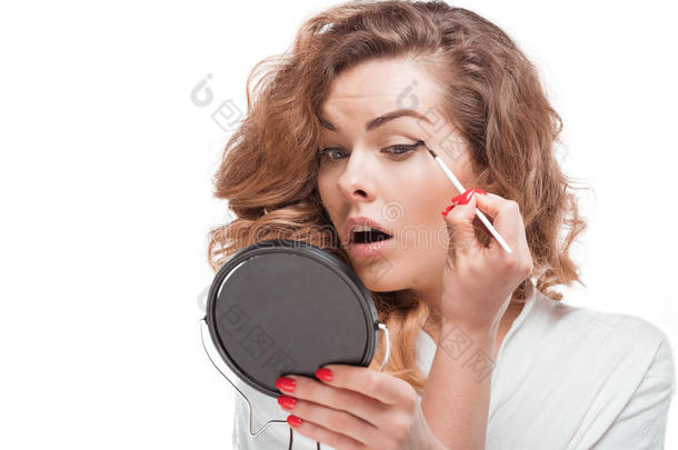 集中的女人有样子的在镜子在期间放置眼线膏