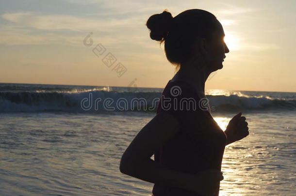 轮廓关于年幼的女人跑步向海海滩在日落.女孩英语字母表的第10个字母