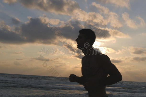 年幼的像运动家的男人跑步向指已提到的人海海滩在日落.运动员的Guam关岛