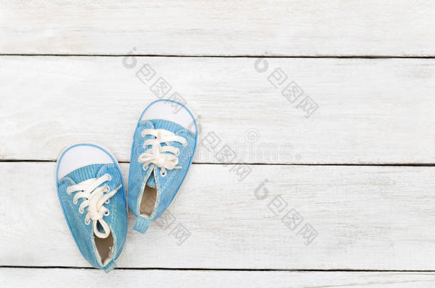 蓝色旅游鞋为一小的男孩向一白色的木制的b一ckground.鹿皮鞋