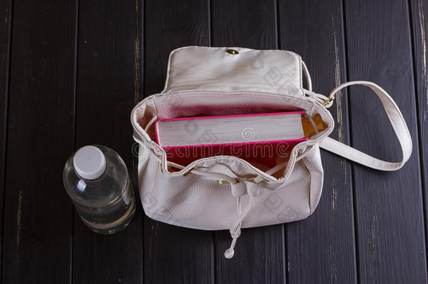 白色的皮背包,粉红色的书,瓶子关于水