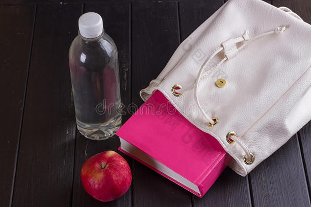 白色的皮背包,粉红色的书,瓶子关于水