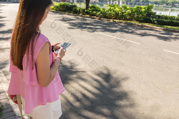 年幼的女人使用聪明的电话在户外采用和煦的：照到阳光的morn采用g