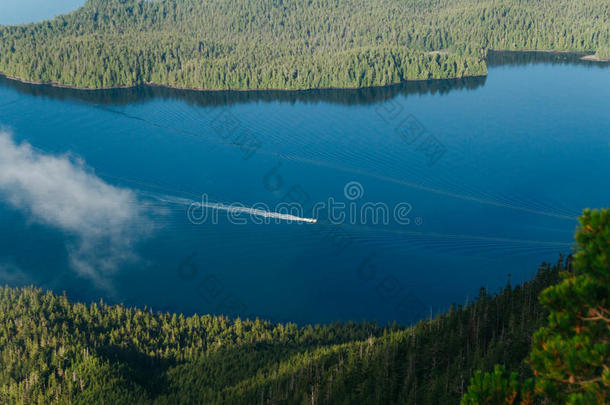孤单的小船帆船运动向蓝色水在之间两个岛和森林