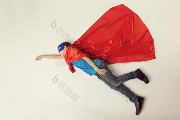 超级英雄小孩飞行的.超级的英雄男孩采用红色的斗篷和蓝色面具.