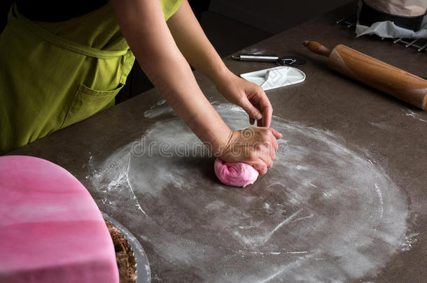 女人准备的粉红色的软糖为蛋糕装饰,手详述