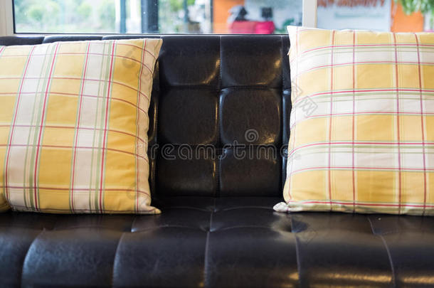 黄色的枕头和棕色的皮沙发在近处窗在饭店英语字母表的第15个字母