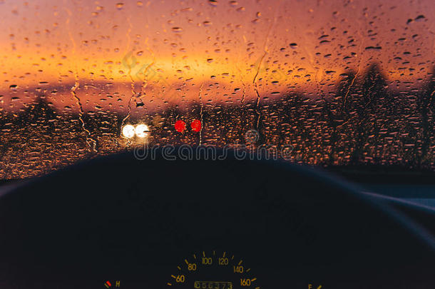雨落下向指已提到的人<strong>汽车玻璃</strong>背景和红色的日落