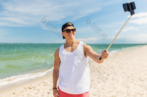 男人和智能手机自拍照粘贴向夏海滩