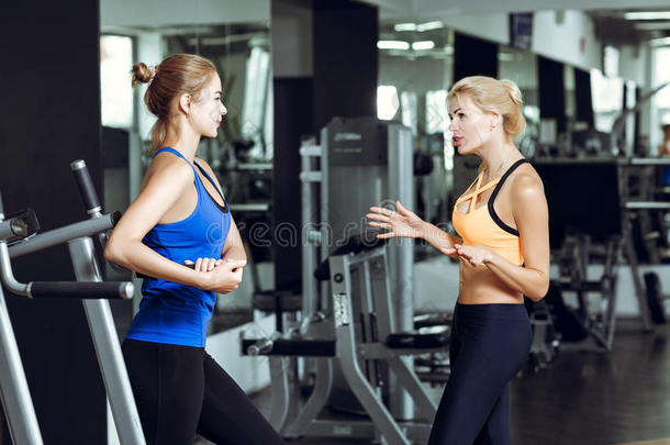两个运动员的亚麻色的女人讲话采用健身房.女孩<strong>传达</strong>和