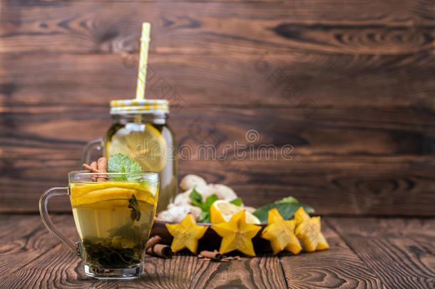 一<strong>杯子</strong>关于柠檬茶水向一木制的b一ckground.绿色的茶水和香料