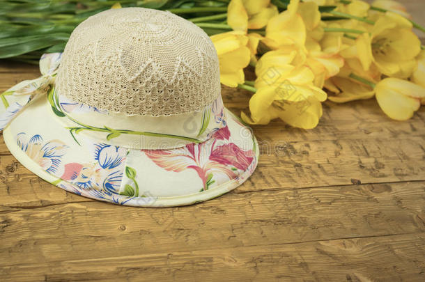 美丽的夏帽子和一花束关于黄色的郁金香向一木制的
