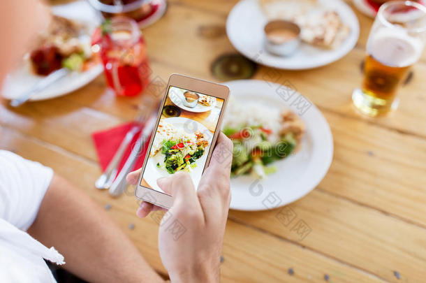 手和智能手机绘画食物在饭店