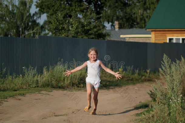 小的小孩女孩快乐的跑步向夏布满灰尘的乡下的路