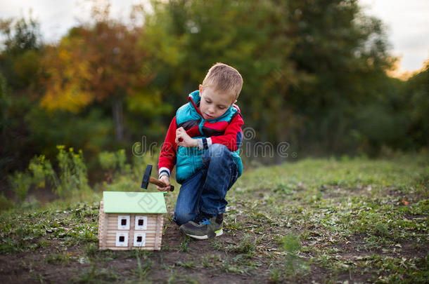 一小的男孩采用一秋森林收集一木制的房屋设计师