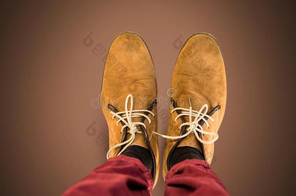 棕色的鞋子向脚和棕色的背景