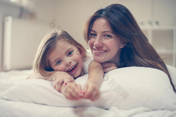 母亲和她漂亮的小的女儿说谎向床.
