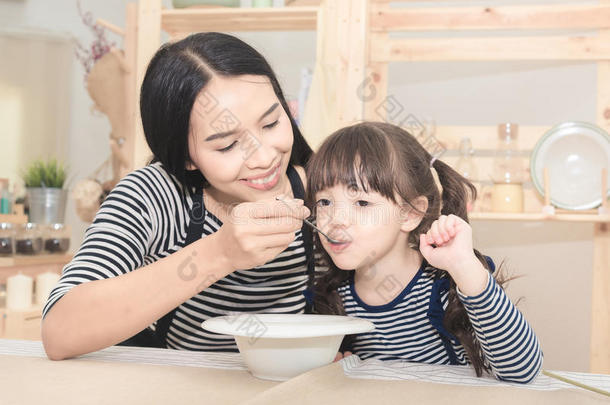 亚洲人妈妈给食健康的早餐向她漂亮的女儿
