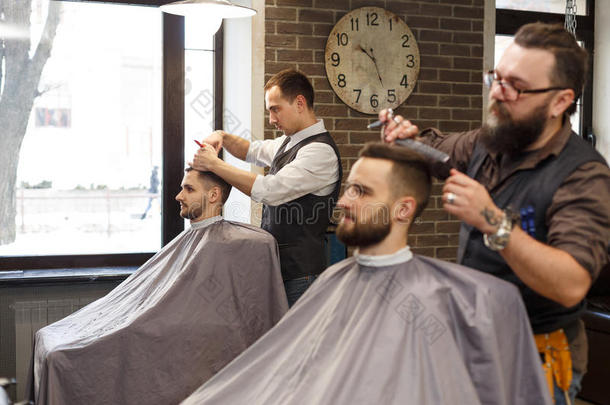 理发师做理发和剪刀向顾客在<strong>理发店</strong>