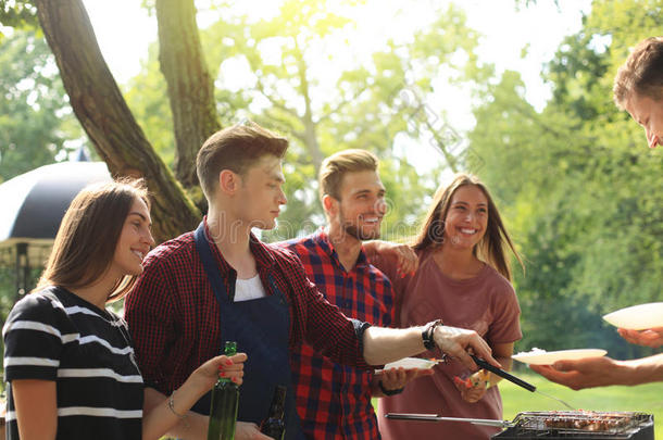 幸福的朋友烧烤肉和享有烤架社交聚会在户外
