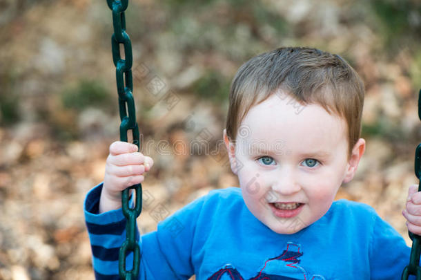 年幼的男孩所有乐趣在外面在公园向一pl一yground摇摆放置