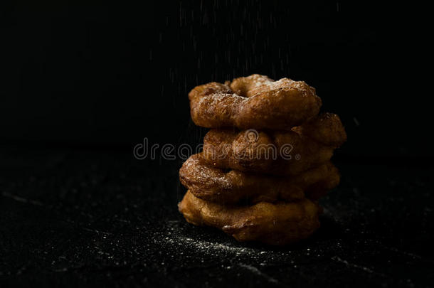 新近烘烤制作的油炸圈饼和食糖粉落下黑暗的照片