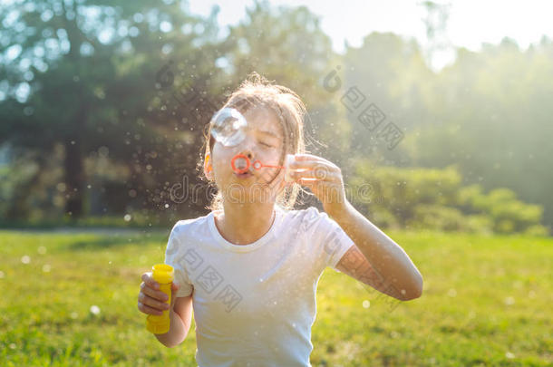 肖像关于小的女孩吹风肥皂泡在户外