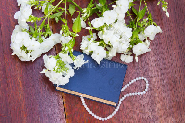书和白色的花和珍珠项链向木制的背景.