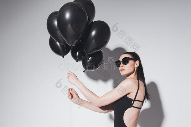 年幼的女人采用太阳镜和游泳衣hold采用g黑的<strong>气球</strong>向