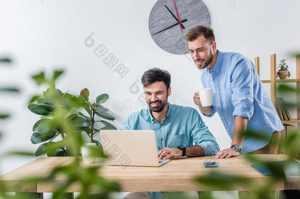 商业同事工作的和便携式电脑在工作场所采用办公室