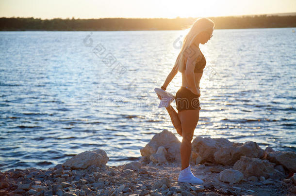 苗条的适合女人向多岩石的海滩伸后的锻炼